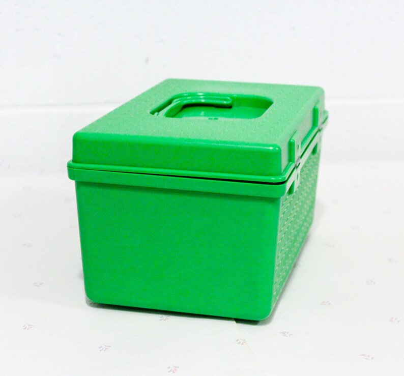 Puede incluir: Una caja de almacenamiento de pl&aacute;stico verde brillante con una tapa con bisagras. La caja tiene una superficie texturizada y una peque&ntilde;a manija en la tapa.