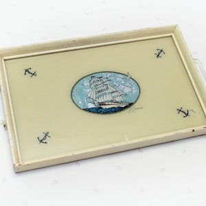 May include: A white wooden tray with a light yellow interior. The tray has a painted image of a ship with sails and four anchors around the edge. The text "J. Jensen" is written in the bottom right corner.
