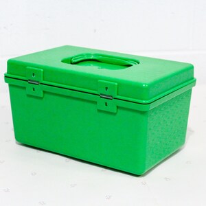 Puede incluir: Una caja de almacenamiento de pl&aacute;stico verde brillante con una tapa con bisagras y una manija de transporte. La caja tiene una superficie texturizada.
