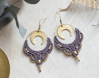 May include: A pair of purple and gold earrings with a crescent moon charm. The earrings are made with macrame and beads.