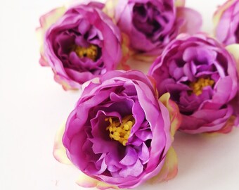 May include: Five purple silk flowers with yellow centers. The flowers are arranged in a cluster on a white background.