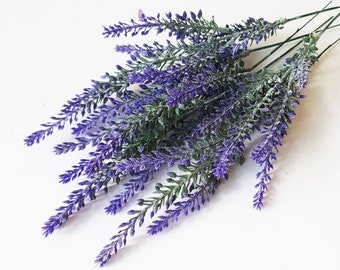 Könnte beinhalten: Ein Bündel künstlicher Lavendelstiele mit leuchtend violetten Blütenähren und grünem Blattwerk. Die Stiele sind dünn und drahtartig an der Basis zusammengefasst, wobei jeder Zweig detaillierte, texturierte Blütenblätter und Blätter aufweist.