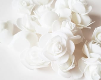 May include: A cluster of small, white, artificial rose buds. The roses are made of a soft, foam-like material and have a realistic appearance.