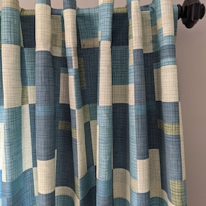 May include: Blue, green, and white geometric patterned curtains with a black curtain rod.