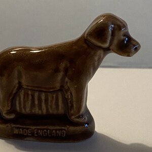 Pu&ograve; includere: Una statuetta di ceramica marrone di un cane in piedi su una base con le parole "Wade England" incise su di essa.