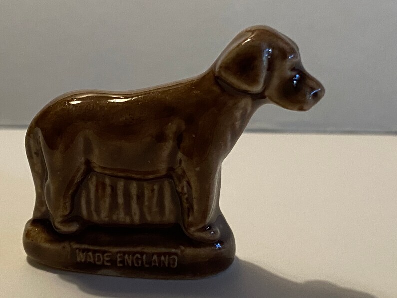 Pu&ograve; includere: Una statuetta di ceramica marrone di un cane in piedi su una base con le parole "Wade England" incise su di essa.