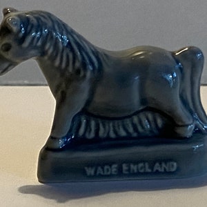 Pu&ograve; includere: Una piccola figurina di ceramica blu di un cavallo, in piedi su una base con le parole "Wade England" incise su di essa.