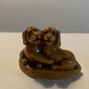 Pu&ograve; includere: Una statuetta in ceramica marrone di due cani che si abbracciano, realizzata da Wade England.
