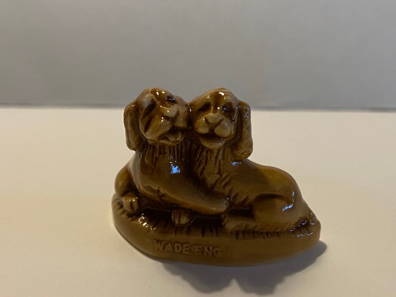 Pu&ograve; includere: Una statuetta in ceramica marrone di due cani che si abbracciano, realizzata da Wade England.