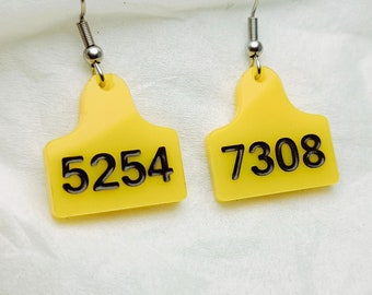 Pendientes amarillos con etiquetas de números de vaca