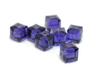 May include: A group of eight purple square-shaped glass beads. The beads are faceted and have a hole in the center for stringing.