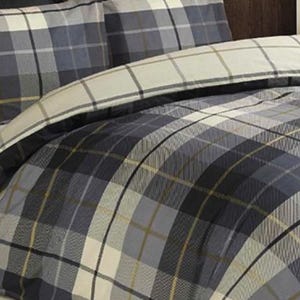 May include: A close-up of a bed set with a plaid design in grey, navy, and cream. The bedding includes a duvet cover and pillowcases. The pattern has a classic, timeless appeal, suitable for a bedroom.