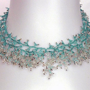 May include: A delicate beaded necklace with a graduated ombre design in shades of turquoise and white. The necklace features a delicate, intricate pattern that resembles branches or coral.