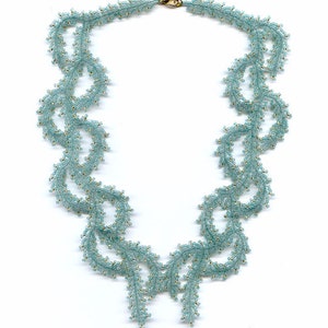 May include: A delicate, light blue beaded necklace with a swirling, leafy design. The necklace is made of small, round beads and has a gold clasp.