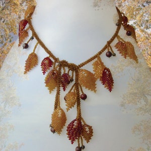 May include: A beaded necklace with a cascading design of gold and burgundy leaves. The necklace is made of small beads and has a delicate, feminine look.