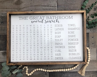 Puede incluir: Un letrero enmarcado en madera con fondo blanco y texto negro. El letrero dice "The Great Bathroom Word Search" e incluye un crucigrama de palabras relacionadas con el baño.