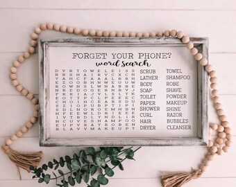 Puede incluir: Un rompecabezas de búsqueda de palabras enmarcado en blanco con el texto "Forget Your Phone? Word Search" en la parte superior. El rompecabezas presenta una cuadrícula de letras con palabras relacionadas con artículos de baño y ducha, como "scrub", "towel", "lather", "shampoo", "body", "soap", "shave", "toilet", "powder", "paper", "makeup", "shower", "shine", "curl", "razor", "hair", "bubbles", y "cleanser".