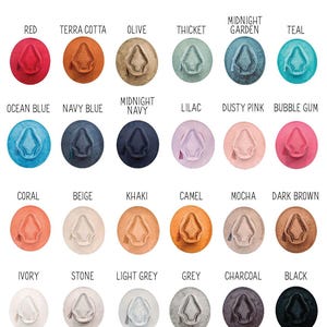 May include: A selection of vegan suede arrow crown hats in a range of colours, such as red, terra cotta, olive, and teal. The hats feature an arrow-shaped crown design and are arranged in a circle, with the colour names above each hat.