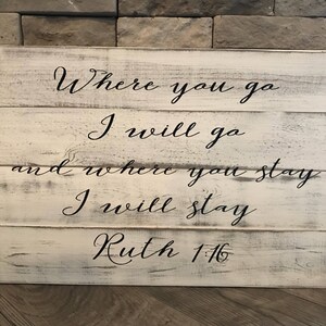 May include: White wooden sign with black lettering that reads "Where you go I will go and where you stay I will stay Ruth 1:16".