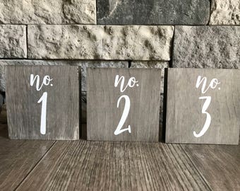 May include: Three rustic wooden signs with white painted numbers and the text "no." on each sign. The signs are numbered 1, 2, and 3.