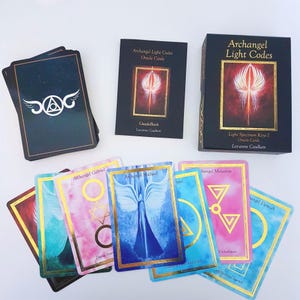 May include: A deck of Archangel Light Codes oracle cards featuring a black box with gold text, a matching guidebook, and several colourful cards displaying angel illustrations, geometric symbols, and names like Archangel Michael and Gabriel.