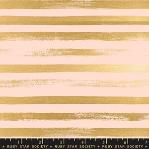 May include: A fabric with a repeating pattern of horizontal gold brushstrokes on a light pink background. The fabric has a ruler along the bottom edge with the text "RUBY STAR SOCIETY".