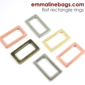 May include: Five flat rectangle rings in different metal finishes: silver, gold, copper, antique brass, and rose gold. The rings are arranged in a semi-circle on a white background. emma line bags.com flat rectangle rings.