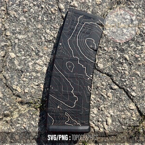 Puede incluir: Un cargador negro con un diseño de mapa topográfico blanco. El cargador es rectangular y presenta un patrón de mapa de contorno detallado. El texto "SVG/PNG: TOPOGRAPHICS" es visible en la parte inferior del cargador.