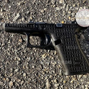 May include: Black handgun with a textured grip, lying on a gravel surface. The gun has the word "INSTANT DOWNLOAD" printed on the top and side. The gun is a semi-automatic pistol.