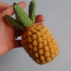 May include: A crocheted pineapple toy with a yellow body and green leaves.