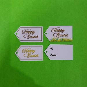 May include: Four white gift tags with a Happy Easter message. Two tags have a gold cursive font, one has a brown cursive font, and one has a brown cursive font with a green grass and blue flower design.