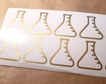 May include: Ten gold-colored vinyl stickers of beakers, each with a graduated scale. The stickers are on a white sheet.