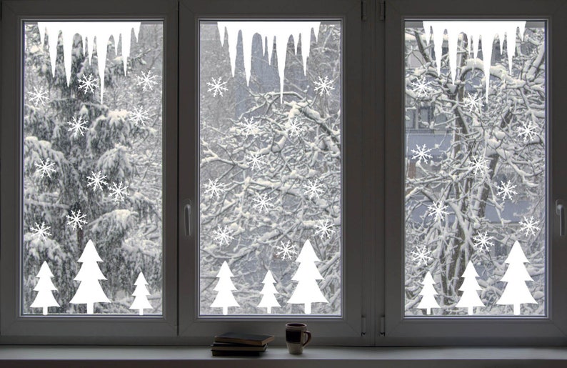 May include: Three windows with white icicle and snowflake decals on the glass. The windows look out onto a snowy winter scene with trees covered in snow.