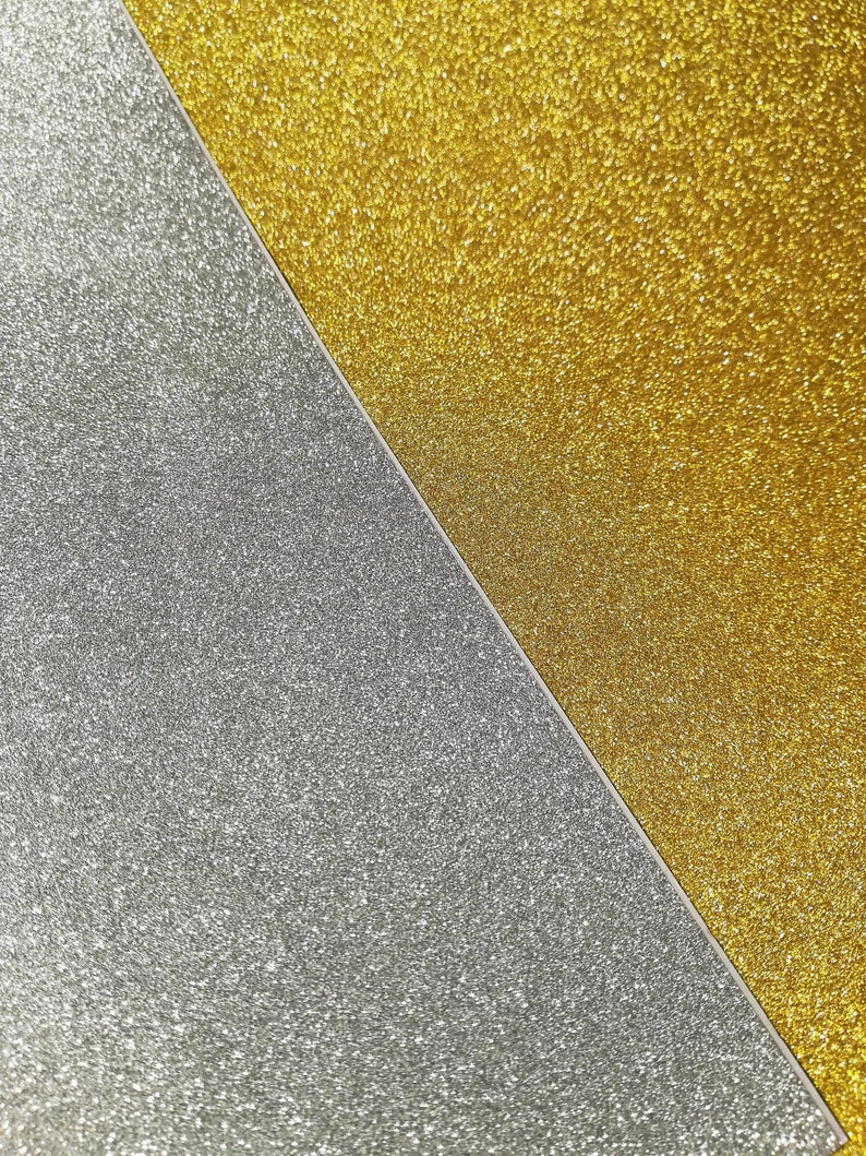May include: A close-up of two pieces of glitter paper, one gold and one silver. The gold glitter paper is on the right side of the image and the silver glitter paper is on the left side of the image. The two pieces of paper meet in a diagonal line.