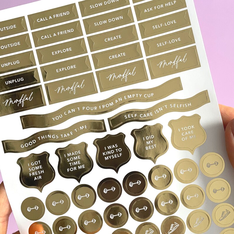 May include: Gold foil stickers with motivational phrases and images, including "Slow Down", "Ask for Help", "Self-Love", "Mindful", "You Can't Pour From an Empty Cup", "Good Things Take Time", "Self-Care Isn't Selfish", "I Was Kind to Myself", "I Did My Best", and "I Took Care of Me".