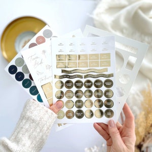 K&ouml;nnte beinhalten: Ein Satz goldfarbener Aufkleber f&uuml;r die Hochzeitsplanung. Die Aufkleber enthalten Etiketten f&uuml;r "Zahlung Anzahlung", "Hochzeitsverwaltung", "Kleiderkauf", "Besichtigung des Veranstaltungsortes", "Kuchenprobe" und "Make-up-Probe".