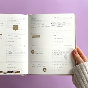 May include: An open journal with daily self-care and gratitude prompts. The journal is open to pages for April 21st and 22nd. The pages are filled with handwritten notes and stickers.