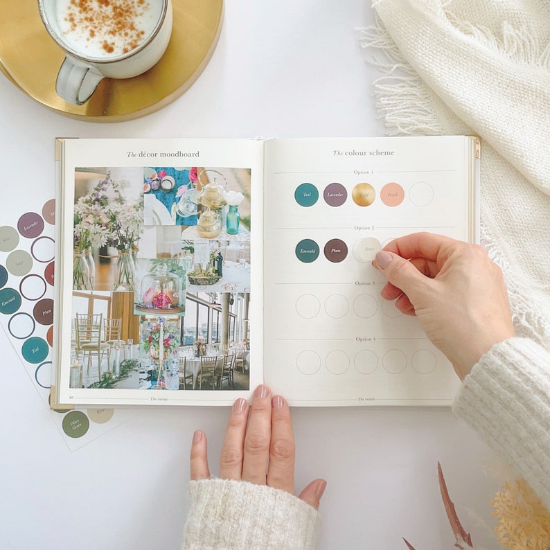 K&ouml;nnte beinhalten: Ein offenes Buch mit einem Dekorations-Moodboard f&uuml;r eine Hochzeit auf der linken Seite und einer Farbpaletten-Auswahlseite auf der rechten Seite. Die Farbpaletten-Auswahlseite hat Kreise zum Ausw&auml;hlen von Farben, mit dem Text "The color scheme" oben. Die Moodboard-Seite hat den Text "The decor mood board" oben.