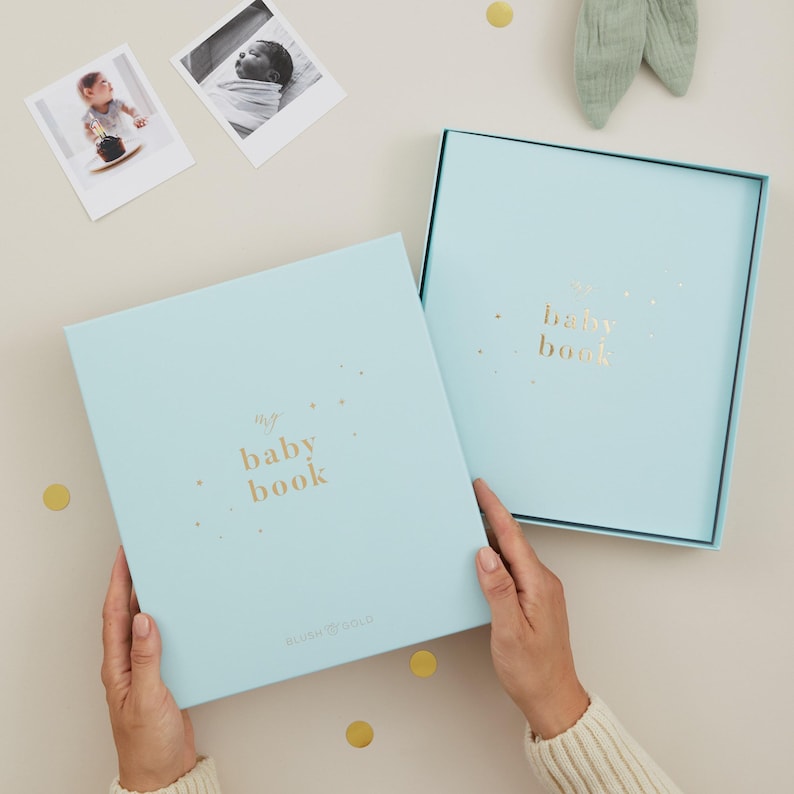 Luxury aqua baby milestone book with a light blue cover and shimmering gold foil accents. This keepsake baby record book includes 114 thoughtfully designed pages for parents to record memories from pregnancy to their child’s fifth birthday, with space for notes and photographs. Gender-neutral in design and inclusive in wording, it is suitable for both boys and girls. Packaged in a coordinating foiled gift box, it makes an ideal baby shower gift.