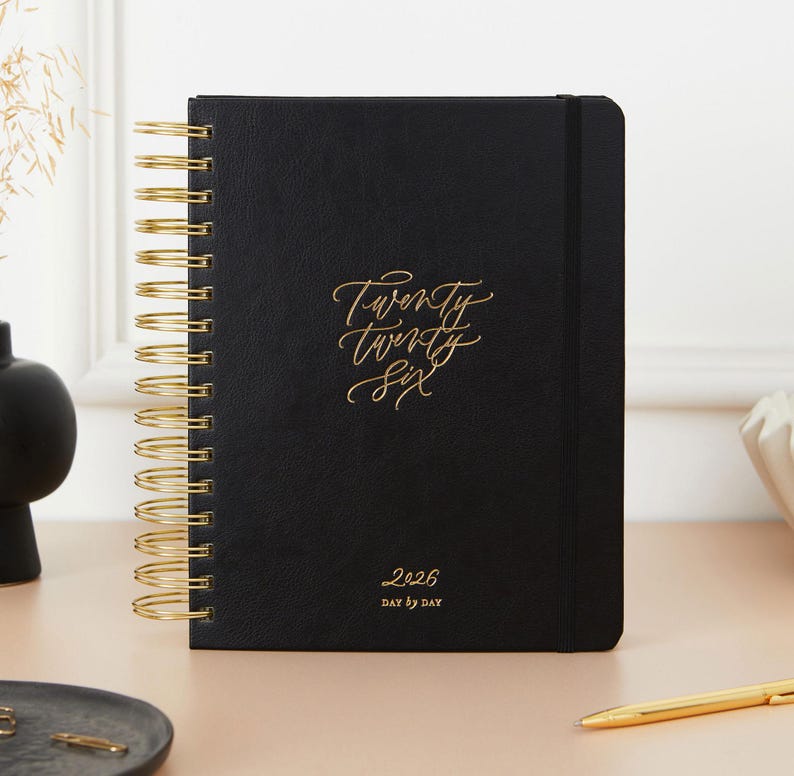 2026 black daily planner vegan leather diary with gold accents, luxury organiser with day-to-view layout and ring binding.