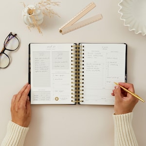 2026 daily planner black vegan leather with gold foiled stickers, tabs, and removable bookmark for organisation.