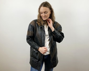 May include: A brown and black leather jacket with a long, relaxed fit. The jacket has a zipper closure and a collar.