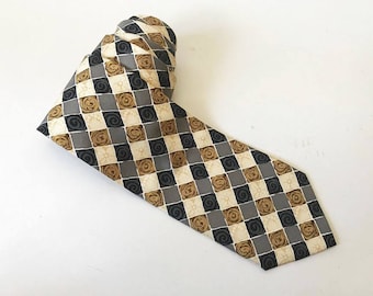 May include: A patterned silk tie with a checkered design in shades of gray, beige, and brown. The pattern features small swirls and floral motifs.