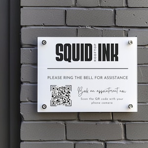 Può includere: Un cartello bianco con testo nero che recita "SQUID ROOFTOP INK" e "PLEASE RING THE BELL FOR ASSISTANCE". Sotto il testo c'è un codice QR in bianco e nero con il testo "Book an appointment now Scan the QR code with your phone camera".