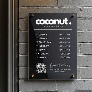 May include: Black sign with white text that reads "coconut. cosmetics". The sign lists business hours for each day of the week. A QR code is in the bottom left corner with the text "Connect with us. Scan the QR code with your phone camera."