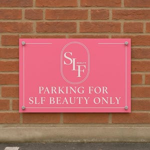 May include: A pink rectangular sign with white lettering and a logo, fixed to a brick wall. The sign states "PARKING FOR SLF BEAUTY ONLY" and displays the "SLF Realty" logo.