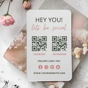 May include: A rectangular white social media sign featuring the text HEY YOU! lets be social, two dark green QR codes labelled FACEBOOK and INSTAGRAM, the text FOLLOW | LIKE | TAG, four social media icons, and the text WWW.YOURWEBSITE.COM.