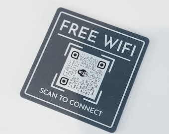Peut inclure: Un panneau carré gris avec du texte blanc qui indique "FREE WIFI" et un code QR noir et blanc avec le texte "WIFI" à l'intérieur. Sous le code QR se trouve le texte "SCAN TO CONNECT".