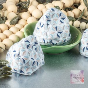 May include: Three blue, white, and brown geometric patterned fabric cones on a green plate. The cones are sitting on a silver surface. The text "B&B Kreations" is visible in the lower right corner of the image.