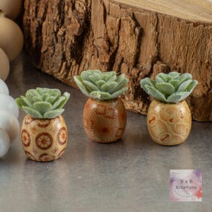 May include: A white ceramic mug with a black handle and the text "But First, Coffee" in a bold, black font. The mug is set against a blurred background, suggesting a cozy setting.